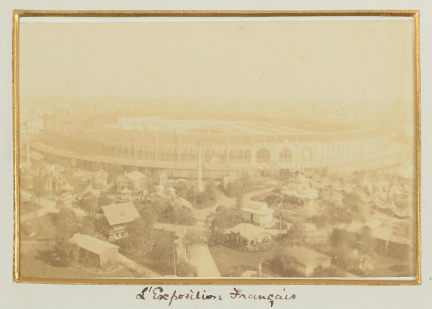 Altes Foto eines Stadions in städtischer Umgebung mit umliegenden Gebäuden, Bäumen und Masten, mit Text am unteren Rand.