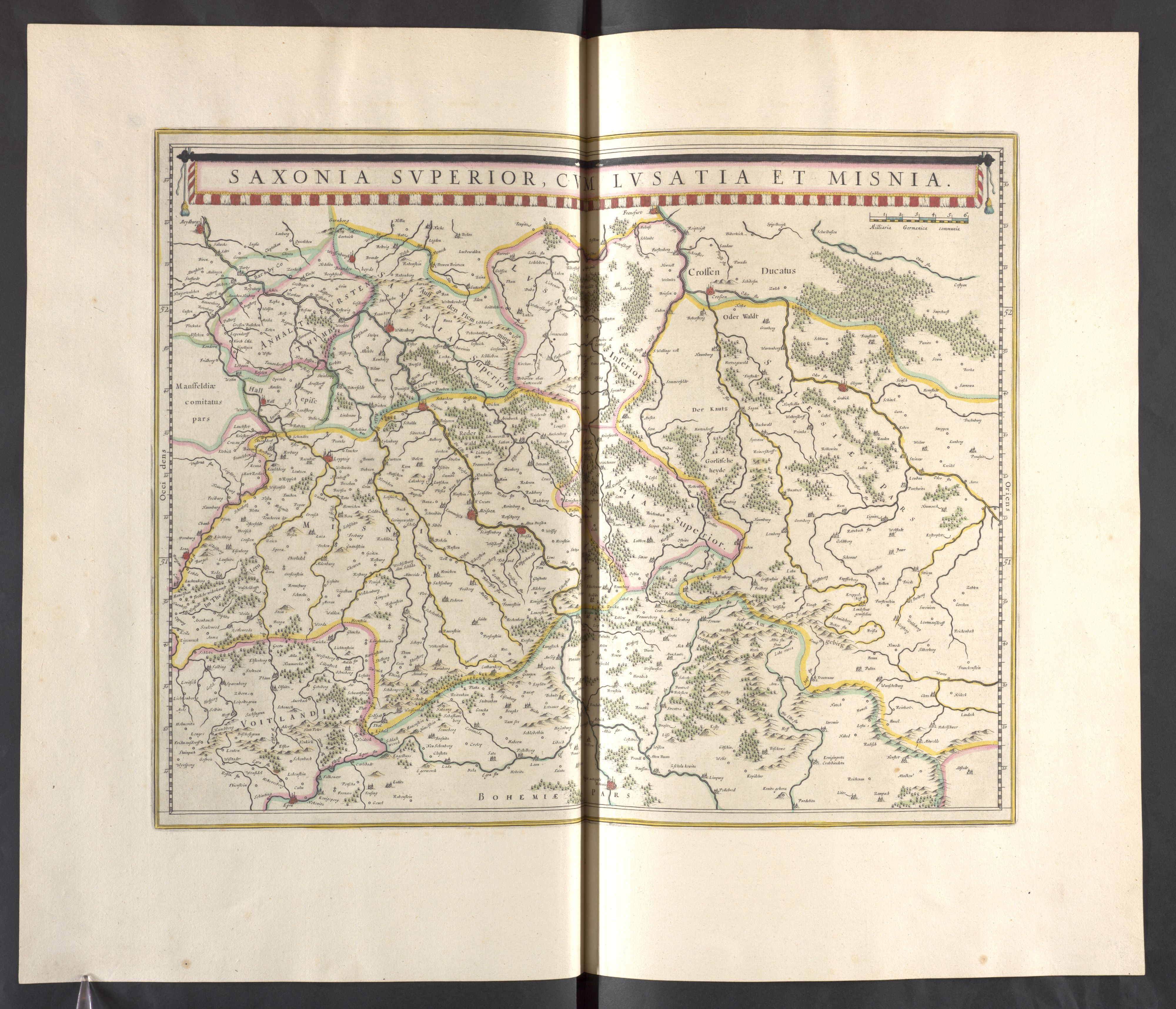 Ein aufgeschlagenes Buch mit einer detaillierten Landkarte von Sachsen, die die Provinzen und Städte hervorhebt, vor einem schwarzen Hintergrund.