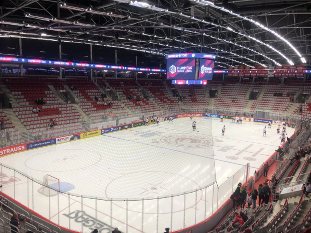 Eishockey-Spiel in einer großen Arena zwischen den St. Louis Blues und den Detroit Red Wings, mit Zuschauern auf den Sitzplätzen und Stehplätzen in der Nähe der Eisfläche, umgeben von einem Zaun und einem Display.