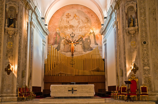 Das Innere einer Kirche mit einer Statue des Jesus Christus in der Mitte und roten St├╝hlen auf der rechten Seite.