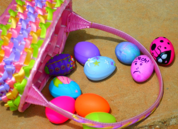 Ein geflochtener Korb mit mehreren bunten Ostereiern an einer Wand.