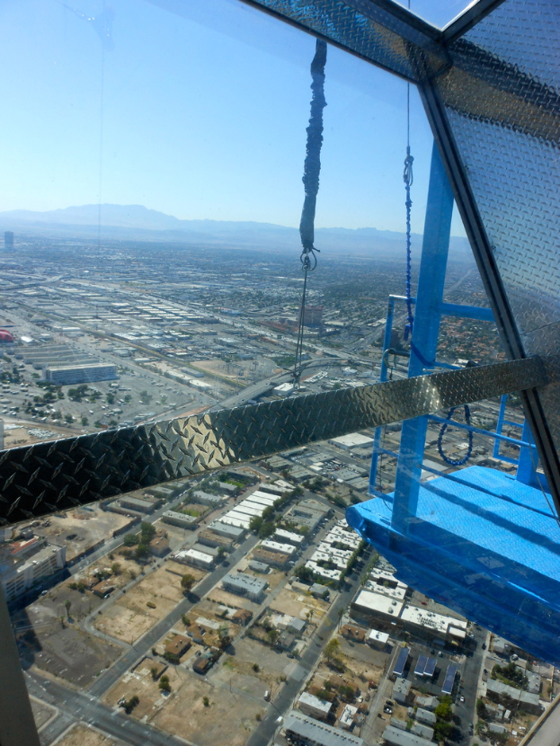 Luftaufnahme einer Stadt mit Häusern, Bäumen, einer Brücke auf der linken Seite, Hügeln im Hintergrund und Himmel darüber.