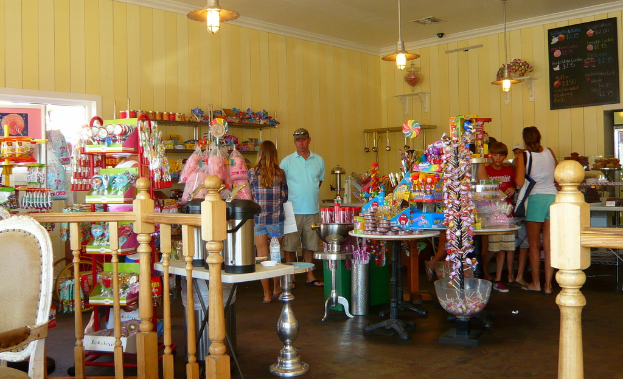 Eine Gruppe von Menschen vor einem Laden mit Lollis, Sü√üigkeiten und Backwaren.