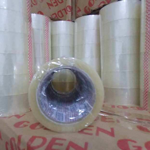 Eine Rolle durchsichtiges Bopp-Packband mit gedrucktem Text darauf, die auf einem Karton liegt.