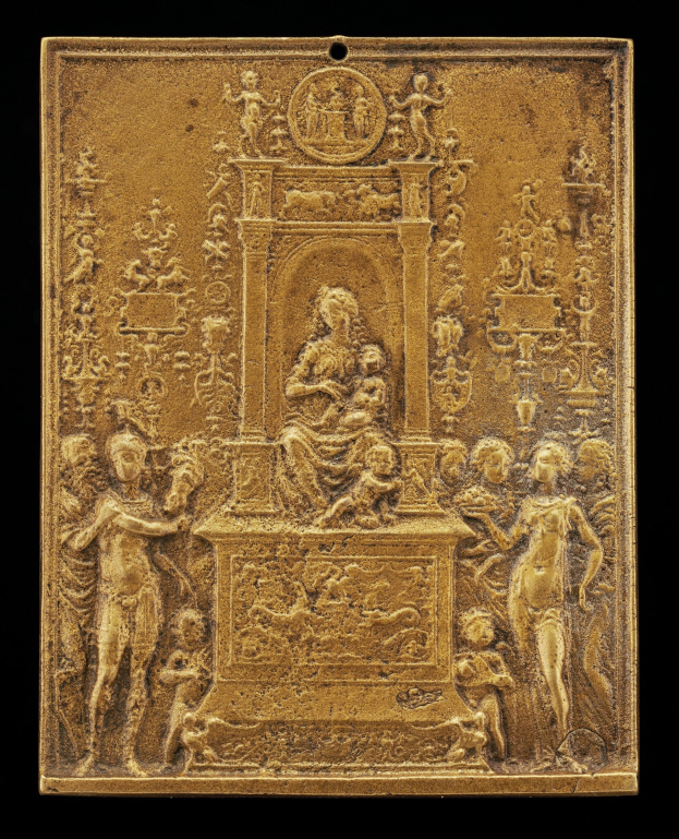 Goldene Plakette mit detaillierter Skulptur einer Frau in einem langen Kleid und eines Mannes in einem Anzug und Krawatte, eingerahmt von einem goldenen Rand gegen einen schwarzen Hintergrund.
