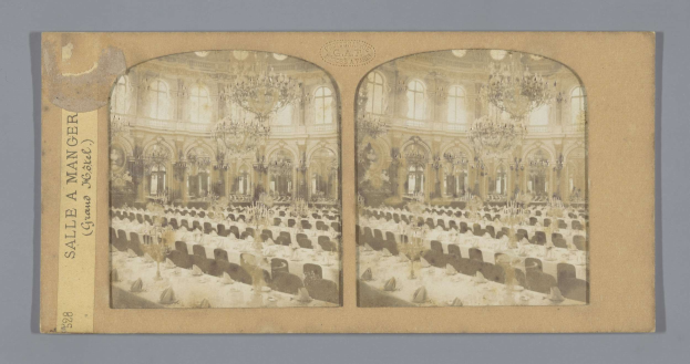 Schwarz-weiß-Foto eines prächtigen Hotel-Speisesaals mit Tischen, Stühlen, Kronleuchtern und Fenstern, mit einer Tafel links mit der Aufschrift "Sale a Manger, Grand Hotel".