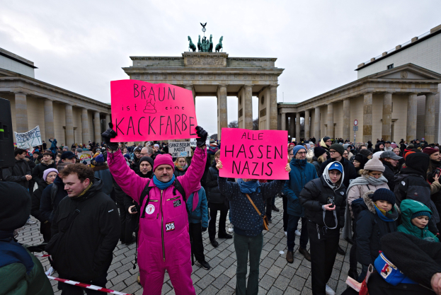 Gruppe von Demonstranten protestiert vor dem Brandenburger Tor in Berlin mit Schildern gegen die Anti-Nazi-Bewegung der deutschen Regierung.