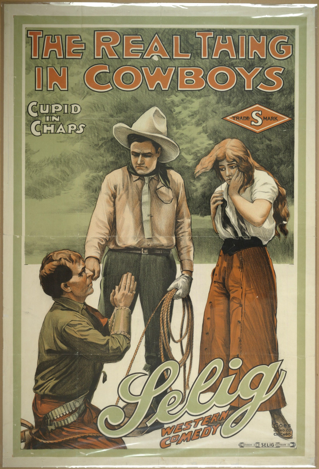 Plakat an einer Wand mit drei Personen - zwei Männer mit Cowboyhüten und eine Frau in einem langen Kleid - mit der Aufschrift "Das echte Ding bei Cowboys" in fetter schwarzer Schrift auf einem hellgelben Hintergrund.