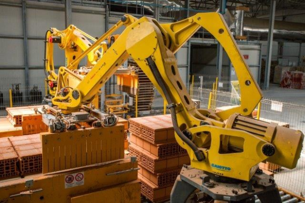 Ein großes Lagerhaus voller numerous boxes, Kräne, ein Zaun, Masten und andere industrielle Ausrüstung, mit einer Wand im Hintergrund.