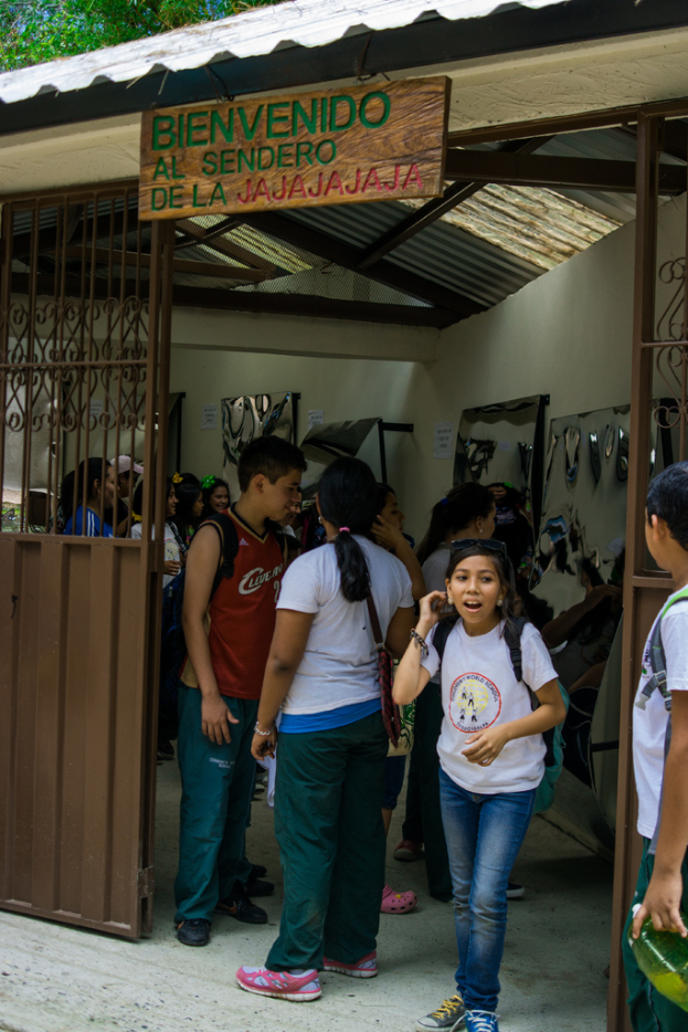 Ein Geschäft mit einem Eisenblechdach und einer Tafel mit Text oben drauf, mit Menschen drinnen.