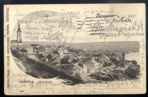 Alte Ansichtskarte mit einer Stadtansicht mit Gebäuden, Bäumen und Wasser sowie teilweise lesbarer Handschrift auf der Vorderseite.