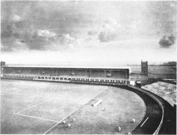 Schwarzes und weißes Foto eines Fußballfeldes mit einem Stadion im Hintergrund, das von Bäumen umgeben ist und einen bewölkten Himmel hat, beschriftet mit "Stoke City Football Club" unten.