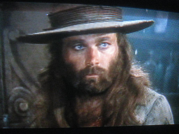 Ein Mann mit Bart und Schnurrbart trägt auf einem Bild eine Mütze.