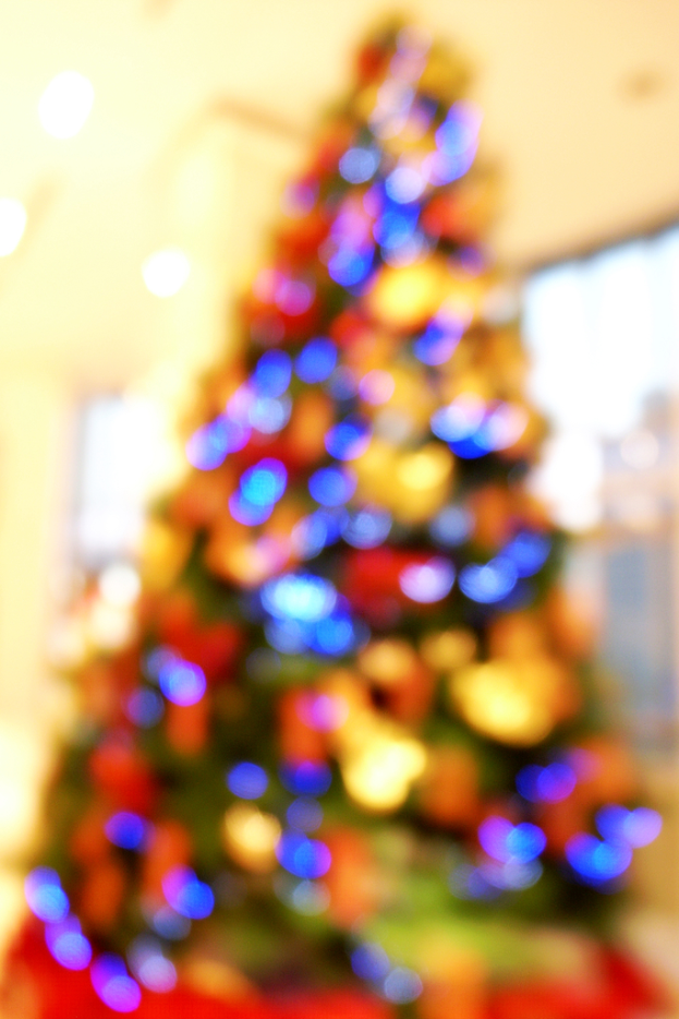 Eine unscharfe Innenaufnahme eines Weihnachtsbaums mit Lichtern und Schmuck in der Mitte.