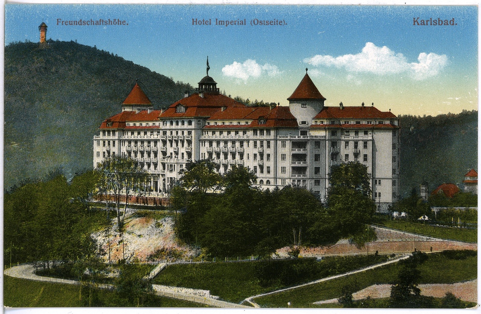 Alte Ansichtskarte des Hotel Imperial in Karlsbad, Deutschland, zeigt ein großes Gebäude mit Fenstern, umgeben von Bäumen, Pflanzen, Gras, einem Pfad, einer Baumgruppe, Hügeln und einem bewölkten Himmel, mit Text oben.