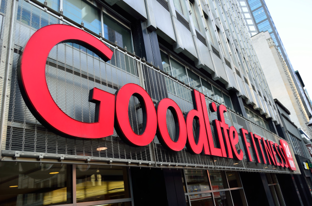 Außenansicht eines Goodlife Fitness Studios in New York City mit Glaswänden, einem Namensschild, benachbarten Gebäuden und einem sichtbaren Himmel im Hintergrund.