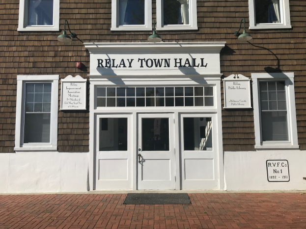 Das Relais Rathaus, ein Gebäude mit Fenstern, Türen, Texttafeln an der Wand, Lampen und einem Türmatte auf dem Boden.