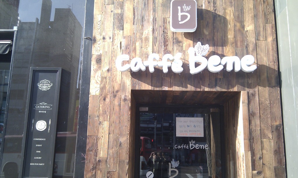 Ein Laden mit der Aufschrift "CAFFE BENES", eine schwarze Tür und eine Glastür.