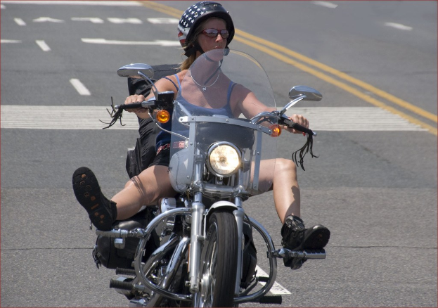 Eine Frau fährt mit dem Fahrrad auf einer Straße und trägt einen schwarzen Helm.
