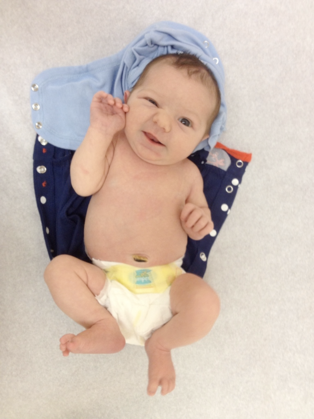 Ein Baby liegt auf zwei Kleidungsstücken.