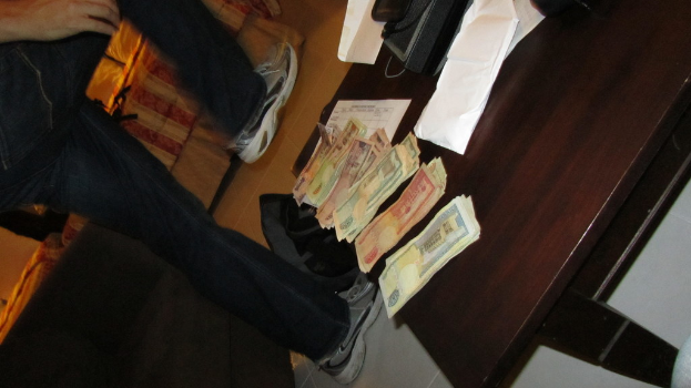 Ein Mann geht neben einem Tisch mit Geld und einem Telefon darauf.