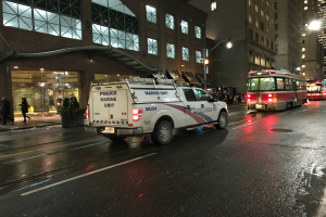 Zwei Männer kehren eine Straße mit Besen, umgeben von Gebäuden, Menschen, Pfählen, Brettern und anderen Gegenständen, mit Text am unteren Bildrand.