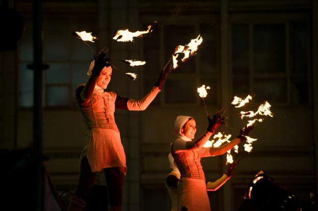 Eine Gruppe von Menschen hält Feuerstöcke vor einem Gebäude.