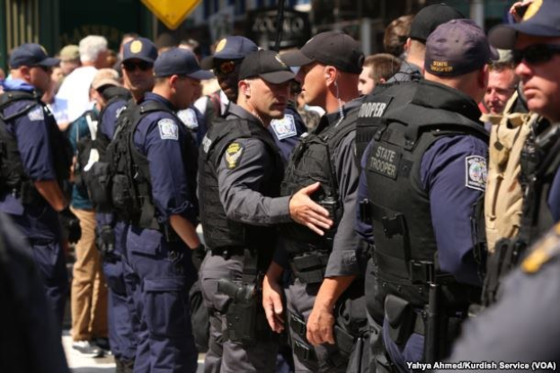 Eine Gruppe von Polizisten in Uniform, die zusammen auf der Straße stehen, einige halten Waffen, mit Gebäuden und Schildern im Hintergrund.