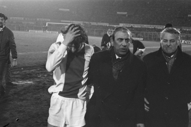 Schwarzes und weißes Foto von Männern, die auf einem Fußballfeld in einem Stadion stehen und enttäuscht nach einem Matchsieg aussehen.