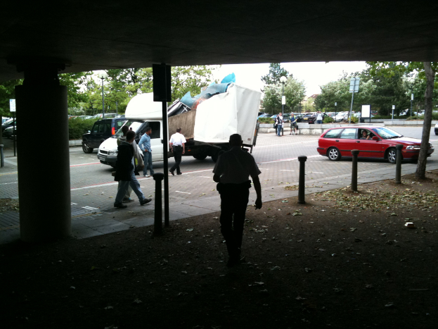 Eine belebte Straßenszene mit zahlreichen Fußgängern, einem Auto und einem Lkw auf der Straße.