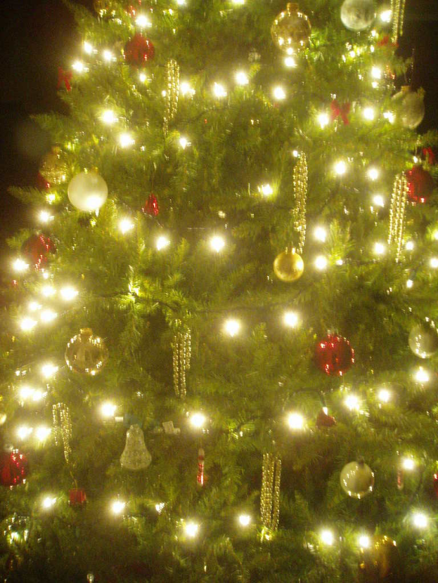 Ein Weihnachtsbaum mit Lichtern, Kugeln und verschiedenen Dekorationen geschmückt.