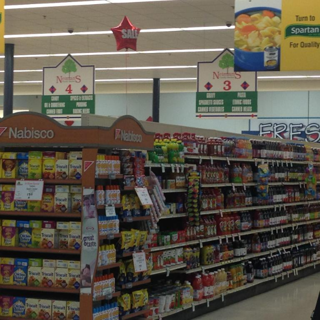 Ein Supermarkt-Innenraum mit Lebensmitteln, Deckenleuchten und Schildern.