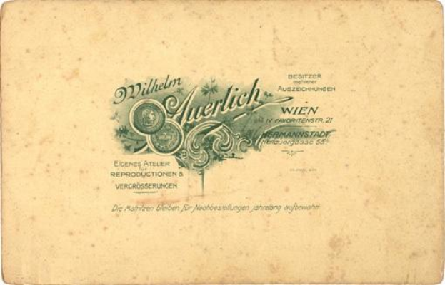 Ein altes deutsches Geldstück mit einem Porträt eines Mannes im Anzug und Krawatte mit ernster Miene, auf dem der Text "Wilhelm Auerlich Wien" gedruckt ist.