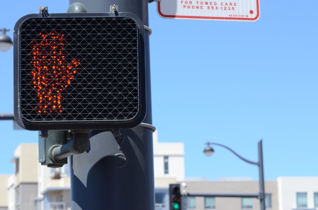Eine Stadtstraßenszene mit Verkehrspfosten, Ampeln, Straßenlaternen, Gebäuden und einem klaren Himmel.
