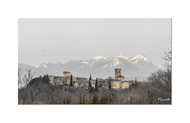 Ein Schloss in der Mitte mit Bäumen unten, Hügel und Himmel im Hintergrund.
