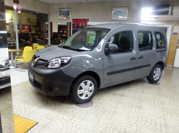 Ein Citroen Berlingo Multispace 1.6 HDI 90CV Feel Wagen steht auf einem Boden umgeben von verschiedenen Gegenständen wie Stühlen, Tischen, Schildern, einem Fernseher, einer Tür, einer Wand mit Fotorahmen und einer Decke mit Deckenleuchten.